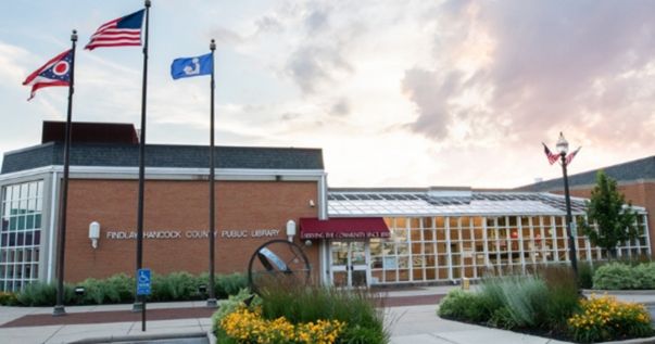 library buildling with yellow flowers out front and american flag flying high