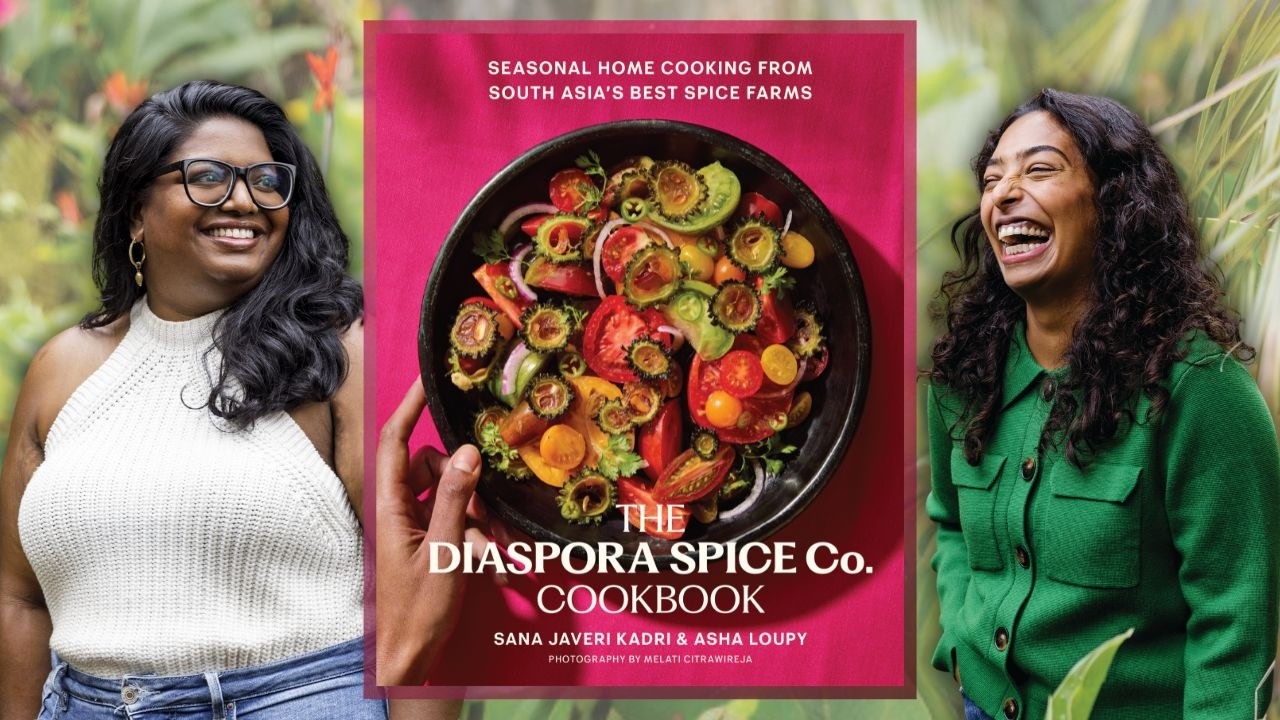 two ladies beside a large book with a pan with a colorful meal in in