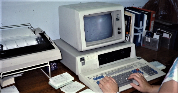persons hand on keyboard of old apple computer