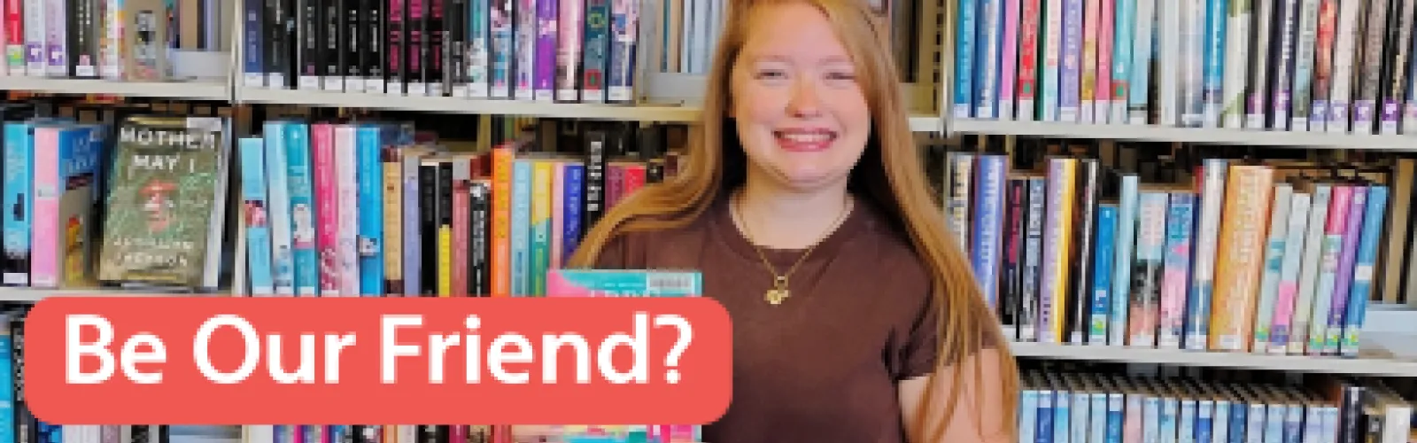 Woman with blonde hair smiling in front of a wall of colorful books